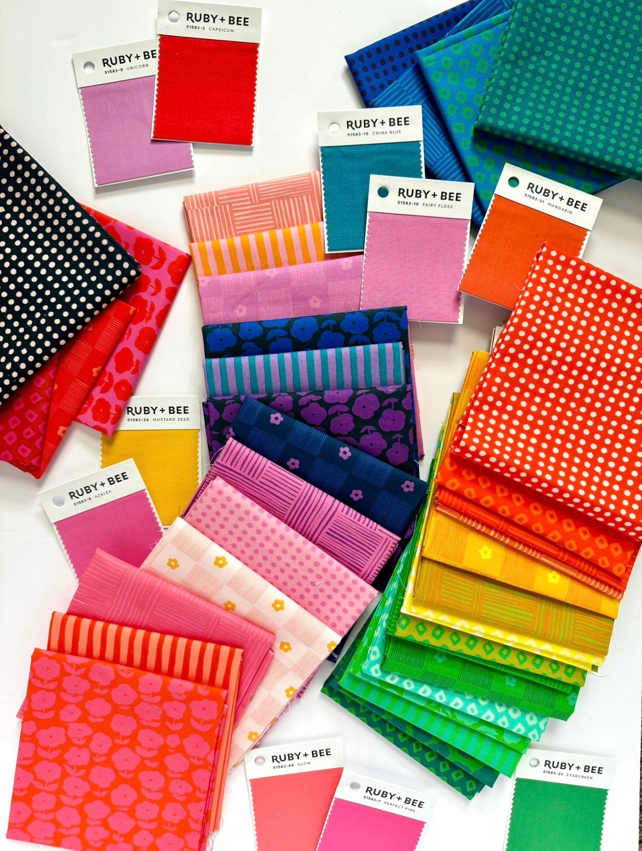 a table topped with lots of different colored fabrics