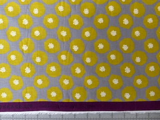 a fabric with a repeating pattern of yellow circles on a gray background. The pattern consists of white circles on a gray background, creating a visually striking design.