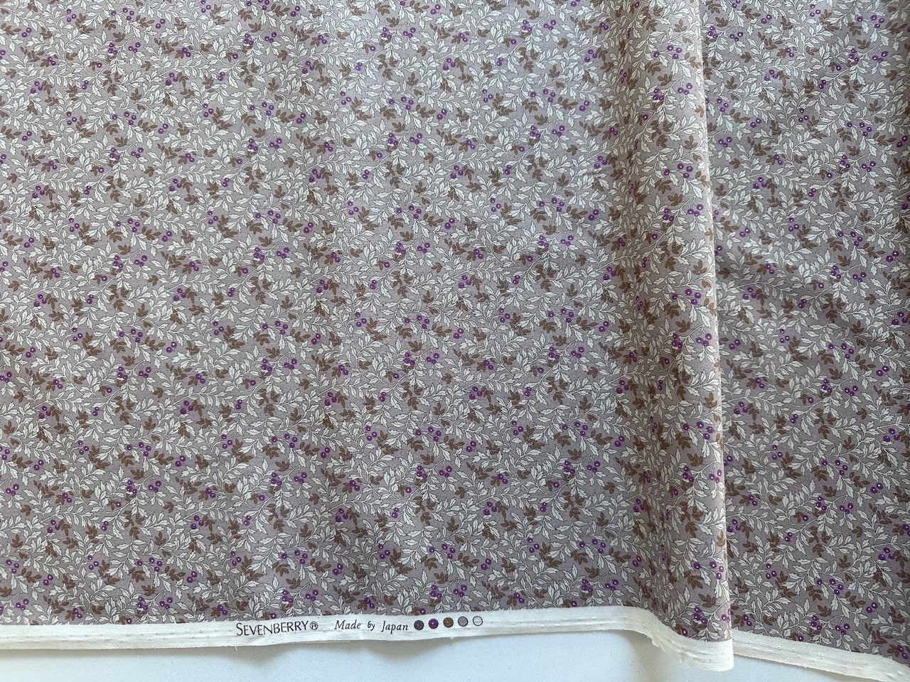 a fabric with a floral pattern, featuring a mix of brown and purple colors. The fabric appears to be made of a material with a floral print, and there is text at the bottom of the fabric that reads "SILVERBERRY Made in Japan".