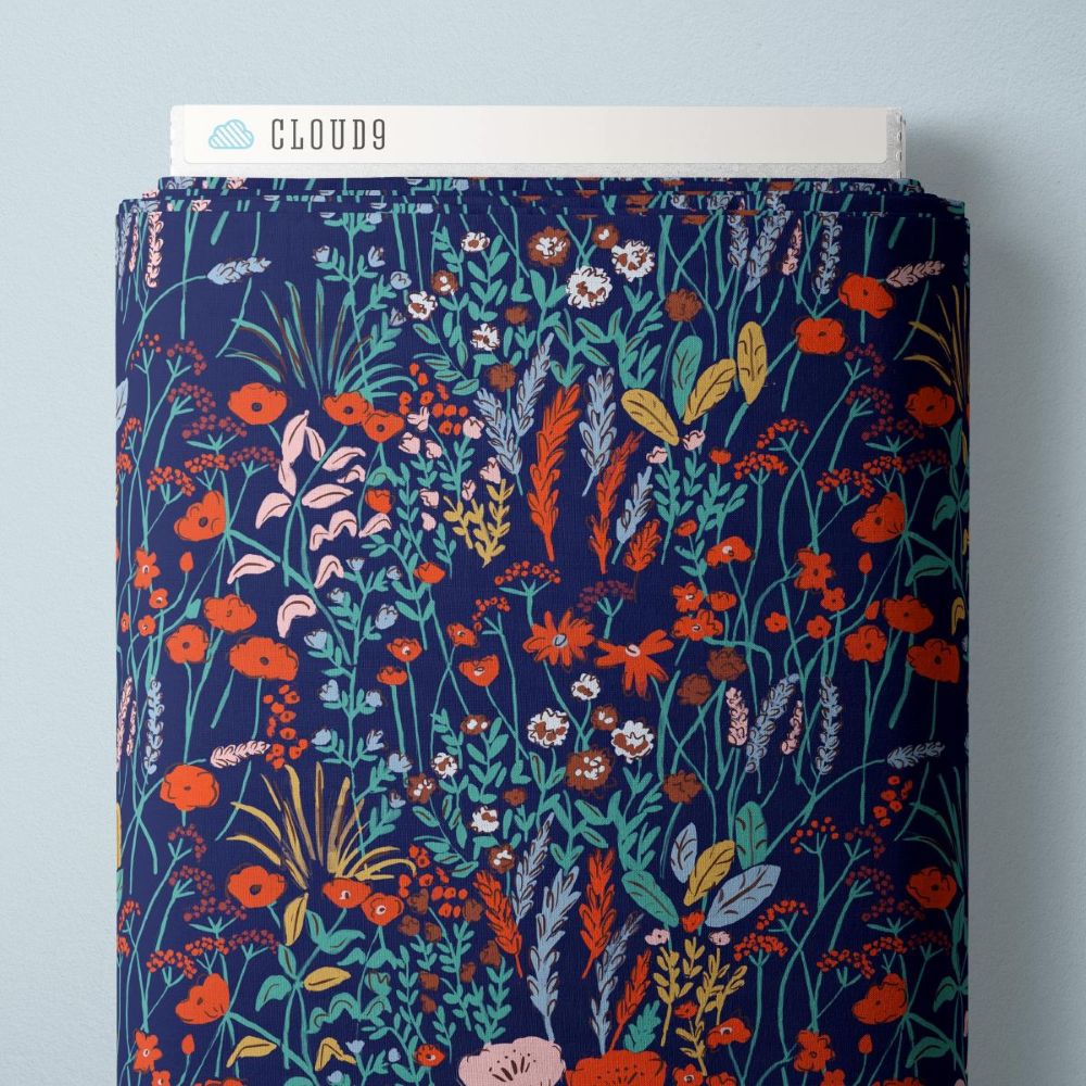 a vibrant floral print with a variety of colorful flowers and leaves, including red, orange, and yellow flowers, as well as green leaves and stems. The print appears to be a fabric or textile with a floral pattern, and there is a white label or tag attached to the top of the print.