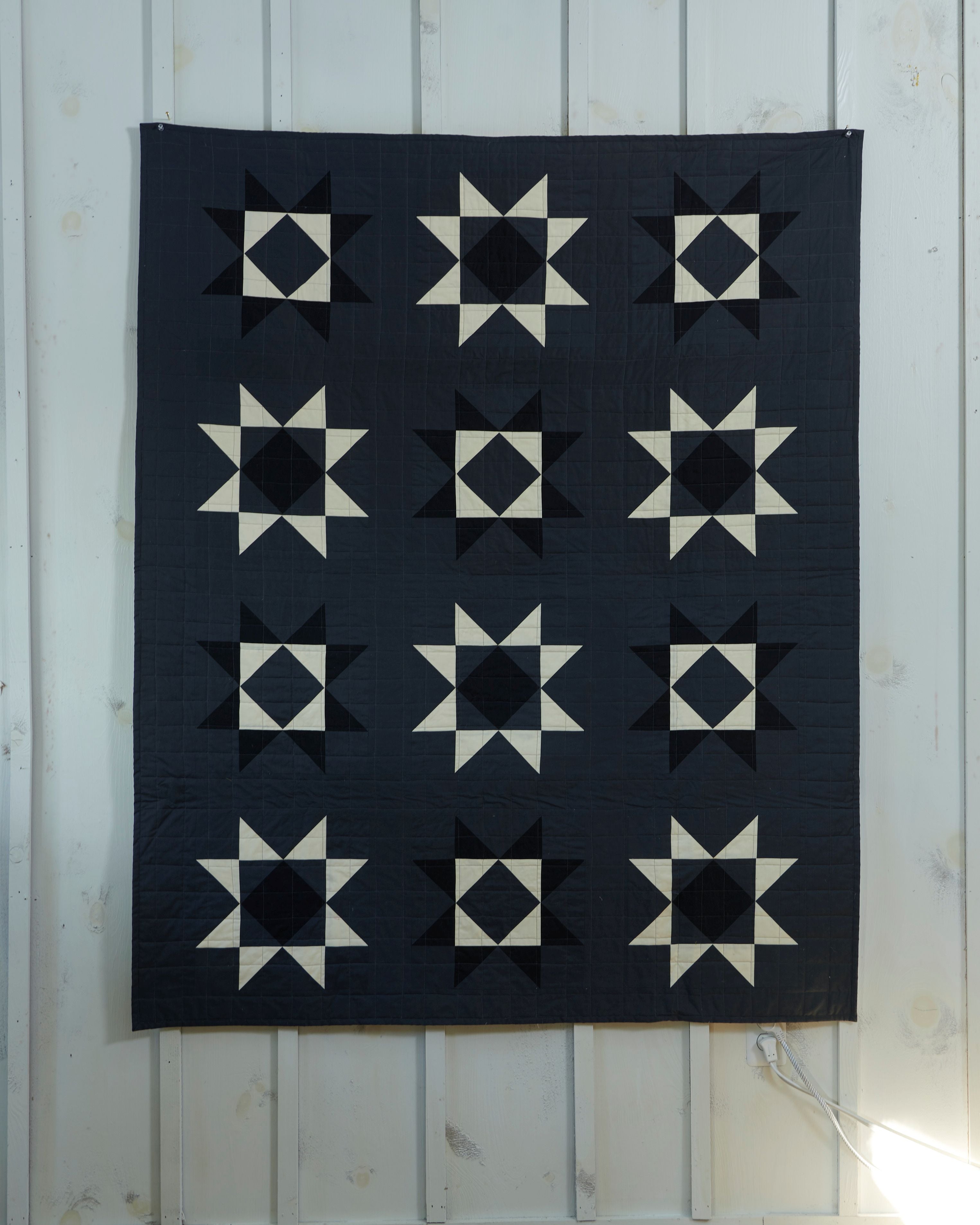 a black and white quilt hanging on a wall