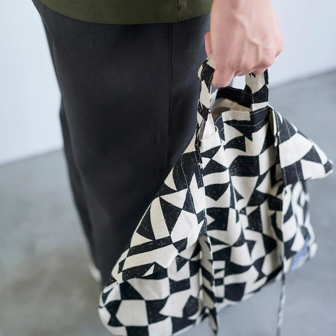 A person is holding a black and white patterned bag in their hand.