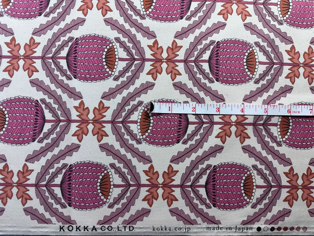 a repeating pattern of pink flowers with leaves on a white background, and a ruler is placed over the pattern to indicate the size.