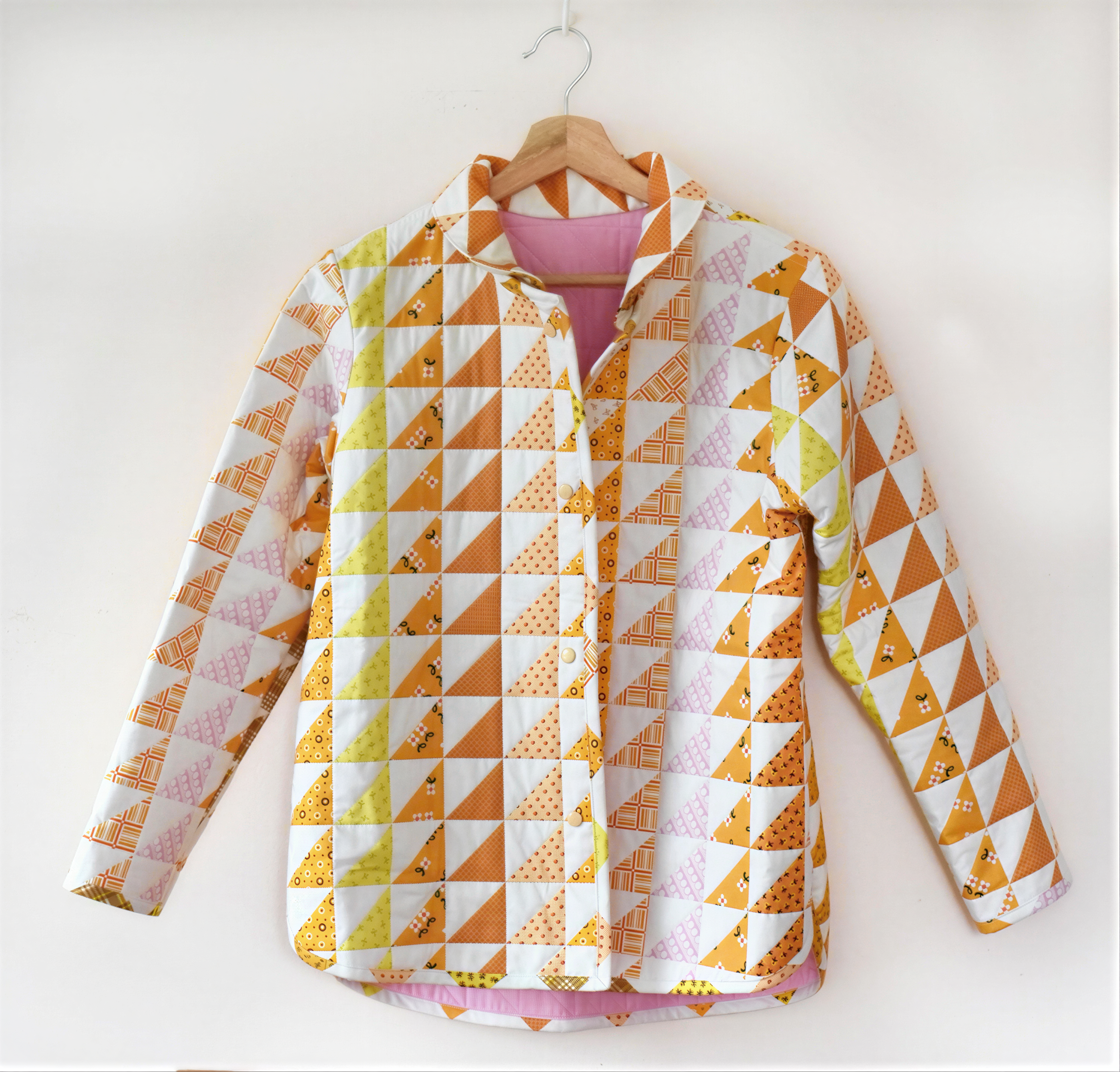 A colorful, patterned shirt hanging on a wooden hanger against a white background.