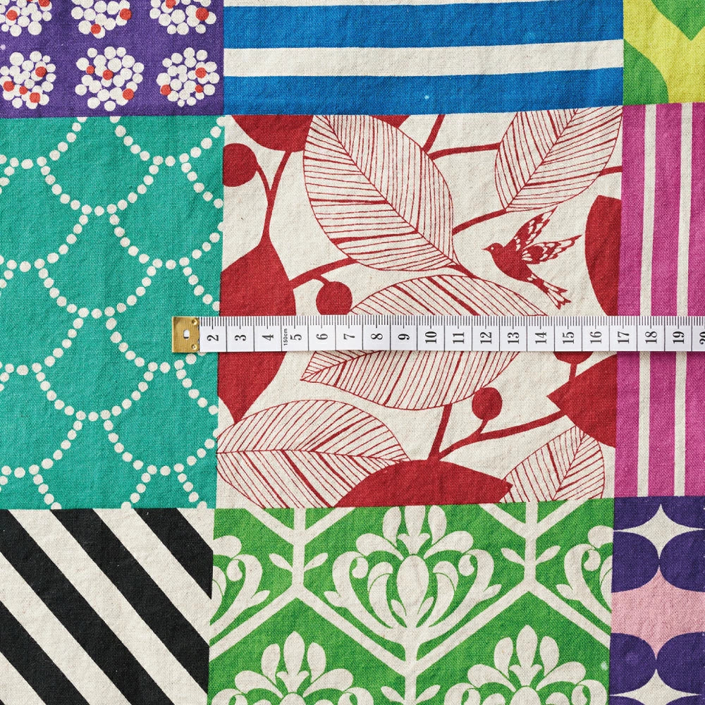 The image is a collage of various colorful and patterned fabric pieces, with a ruler placed in the center to measure the size of the fabric.
