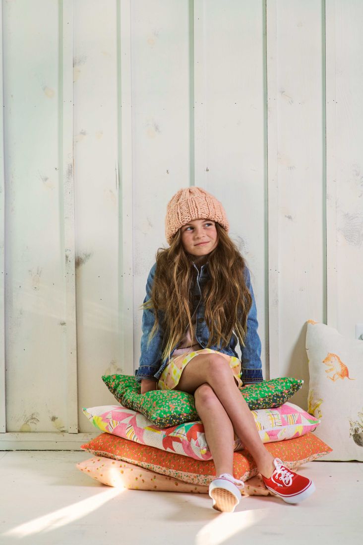 a young girl sitting on a pile of pillows