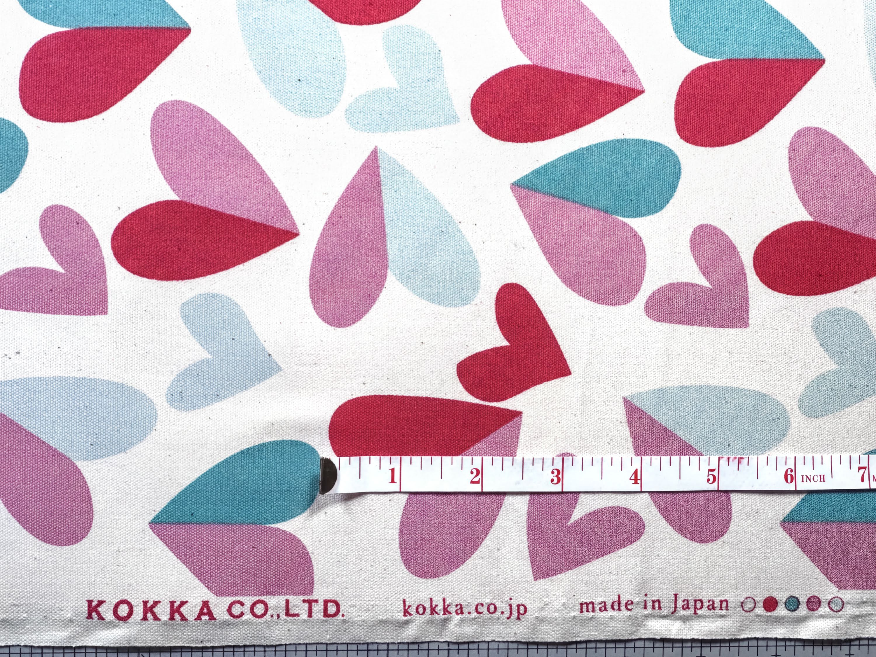 a fabric with a pattern of red and blue hearts, and a ruler for scale.