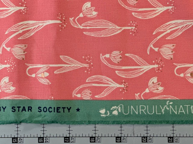 a fabric with a repeating pattern of white flowers on a red background. The fabric is displayed on a ruler for size comparison.
