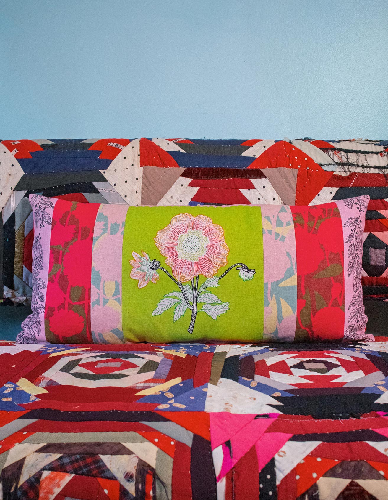 a vibrant, colorful quilt with a large floral pillow resting on top of it.