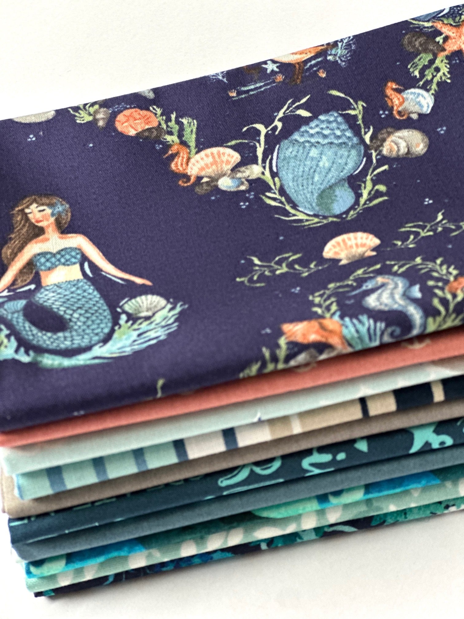 A stack of colorful fabric swatches with a mermaid design printed on them.