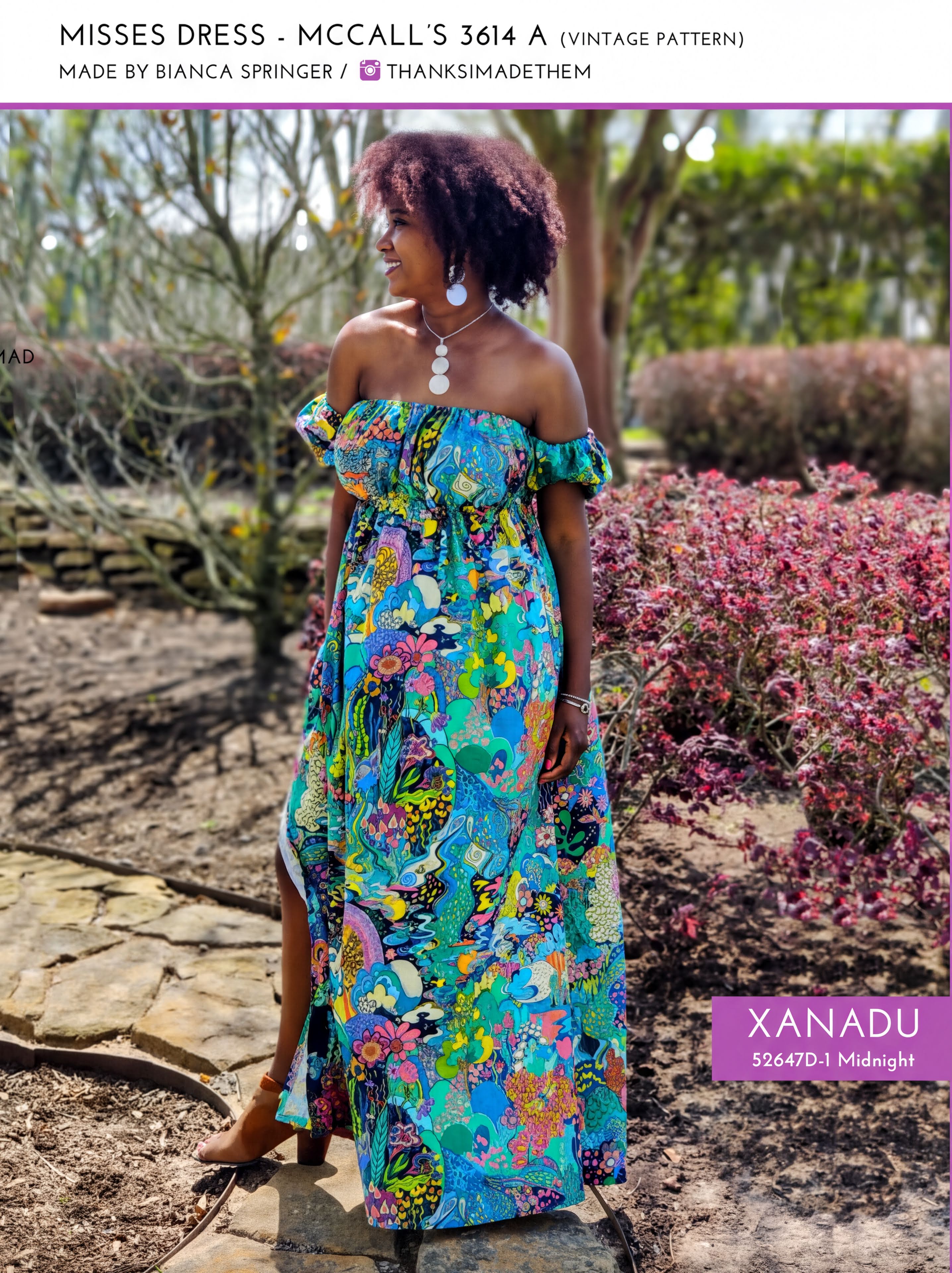 A woman wearing a colorful, patterned dress stands in a garden surrounded by flowers.