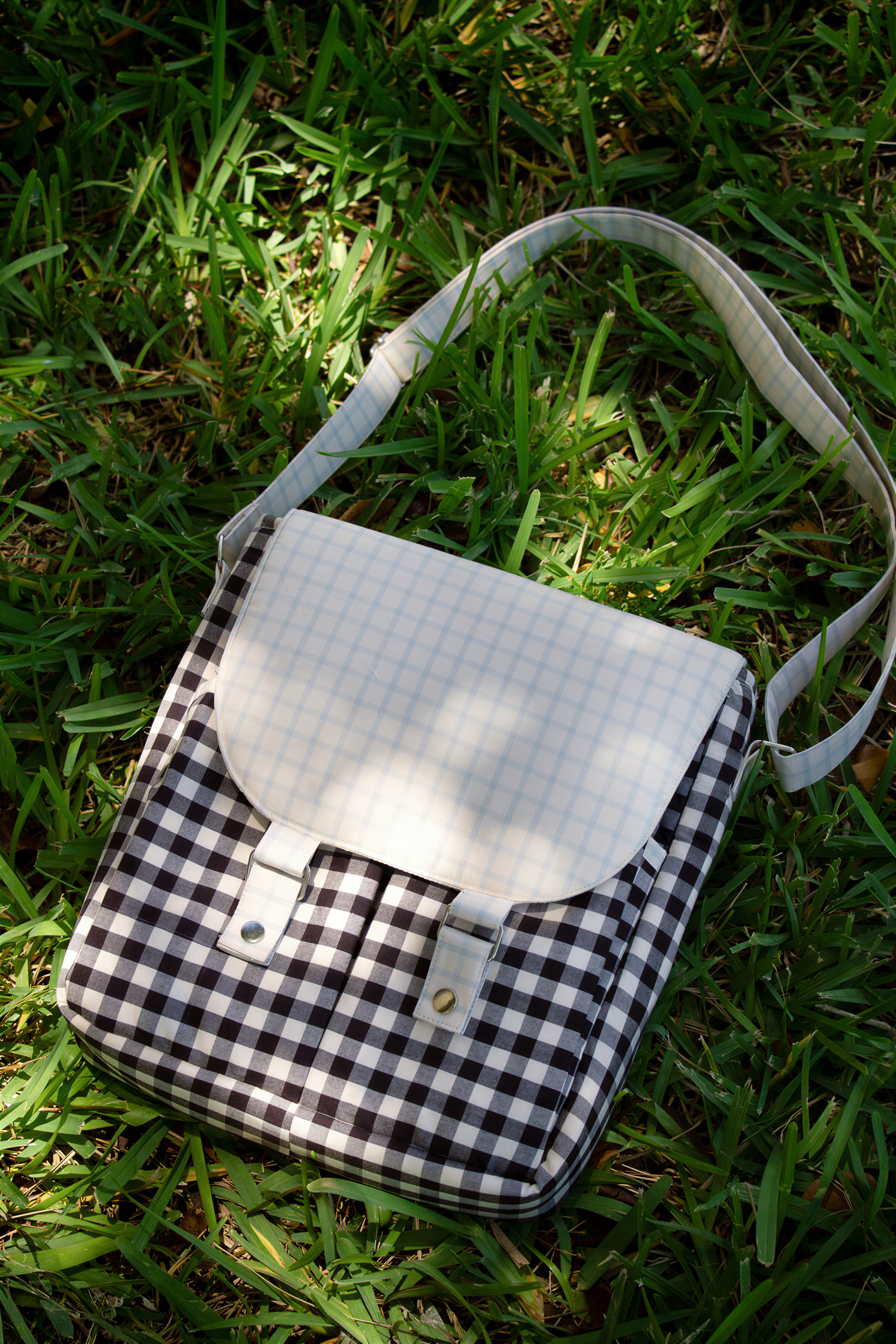 A white and black checkered bag with a white handle rests on the grass.