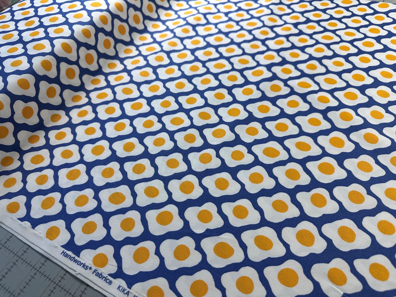 a fabric with a repeating pattern of yellow and white egg shapes, creating a visually striking and vibrant design.