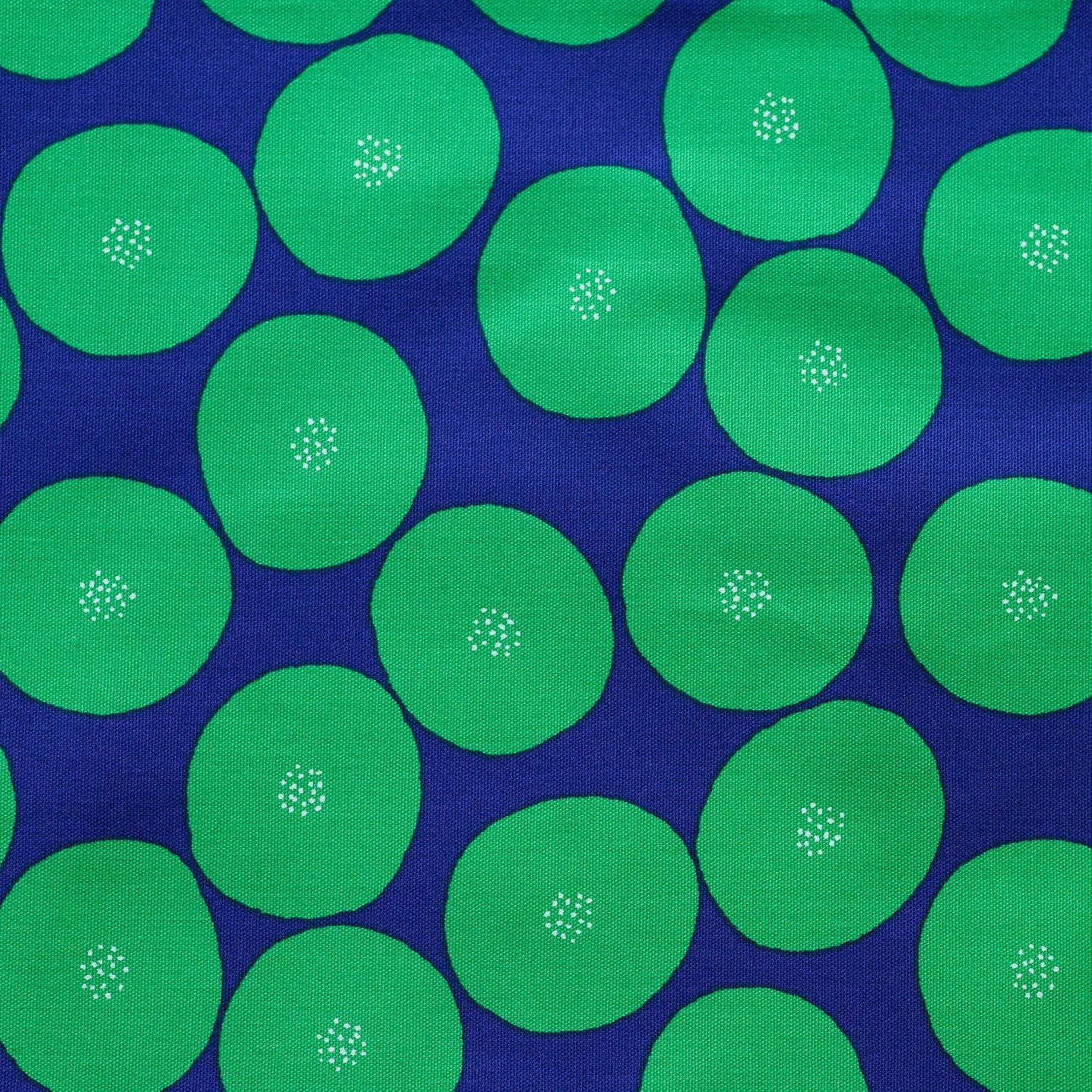 a close-up view of a fabric with a repeating pattern of green circles on a dark blue background.