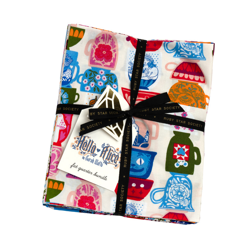 A colorful fabric with various tea-related designs, including teacups, teapots, and other tea-related items, is wrapped in a black ribbon and labeled as a "by Star Society Ruby Star Society" gift.