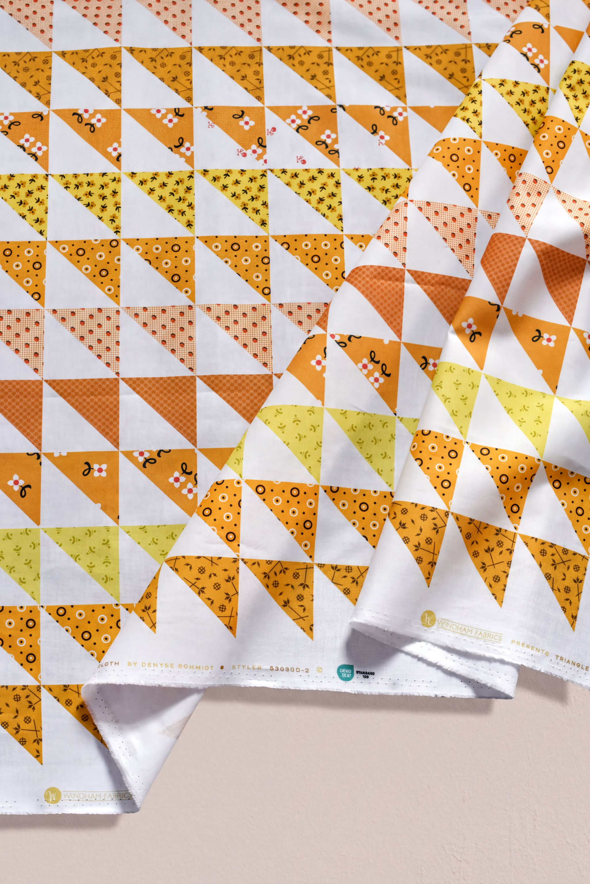 a fabric with a repeating pattern of triangles in various shades of orange and yellow, creating a vibrant and eye-catching design.