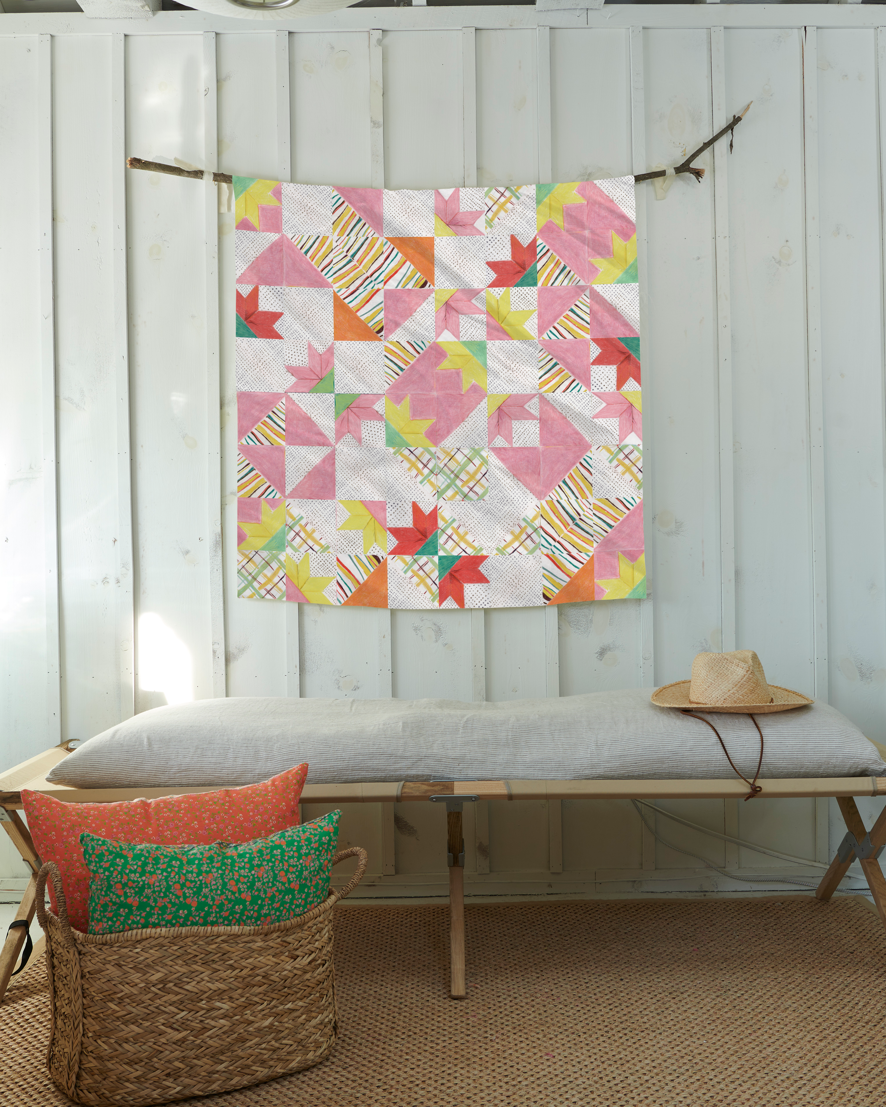 a quilt hanging on a wall next to a bench