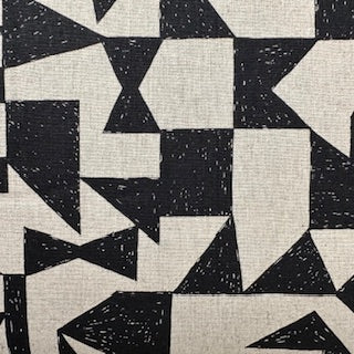 a close-up view of a fabric with a geometric pattern of black and white triangles and rectangles. The pattern is composed of various shapes and sizes, creating a visually striking and abstract design.