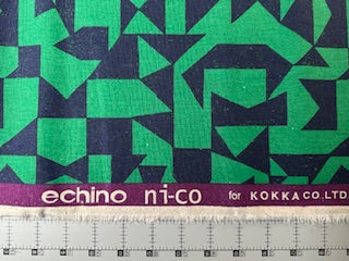 a fabric with a geometric pattern in shades of green and blue, with the text "echino ni-co" and "for KOKKA CO. LTD" printed on it.