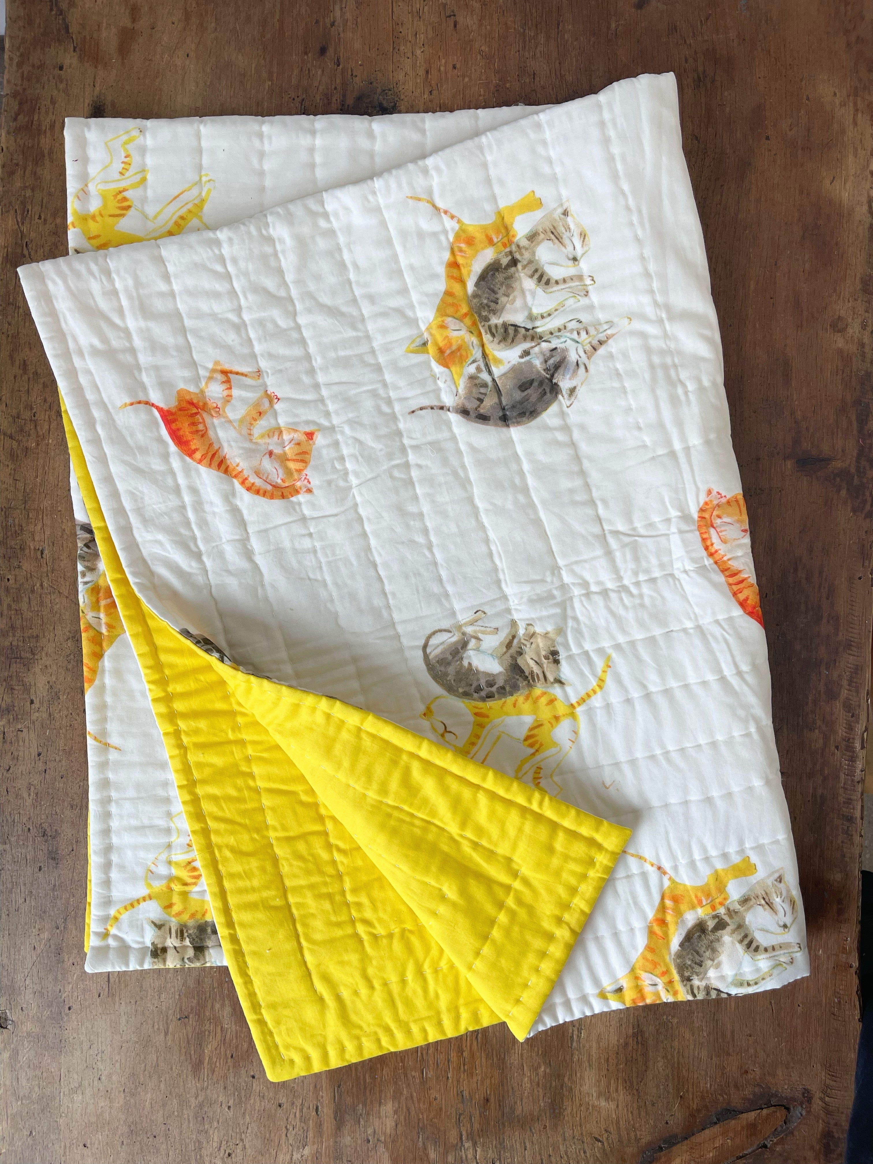 a table topped with a yellow and white quilt