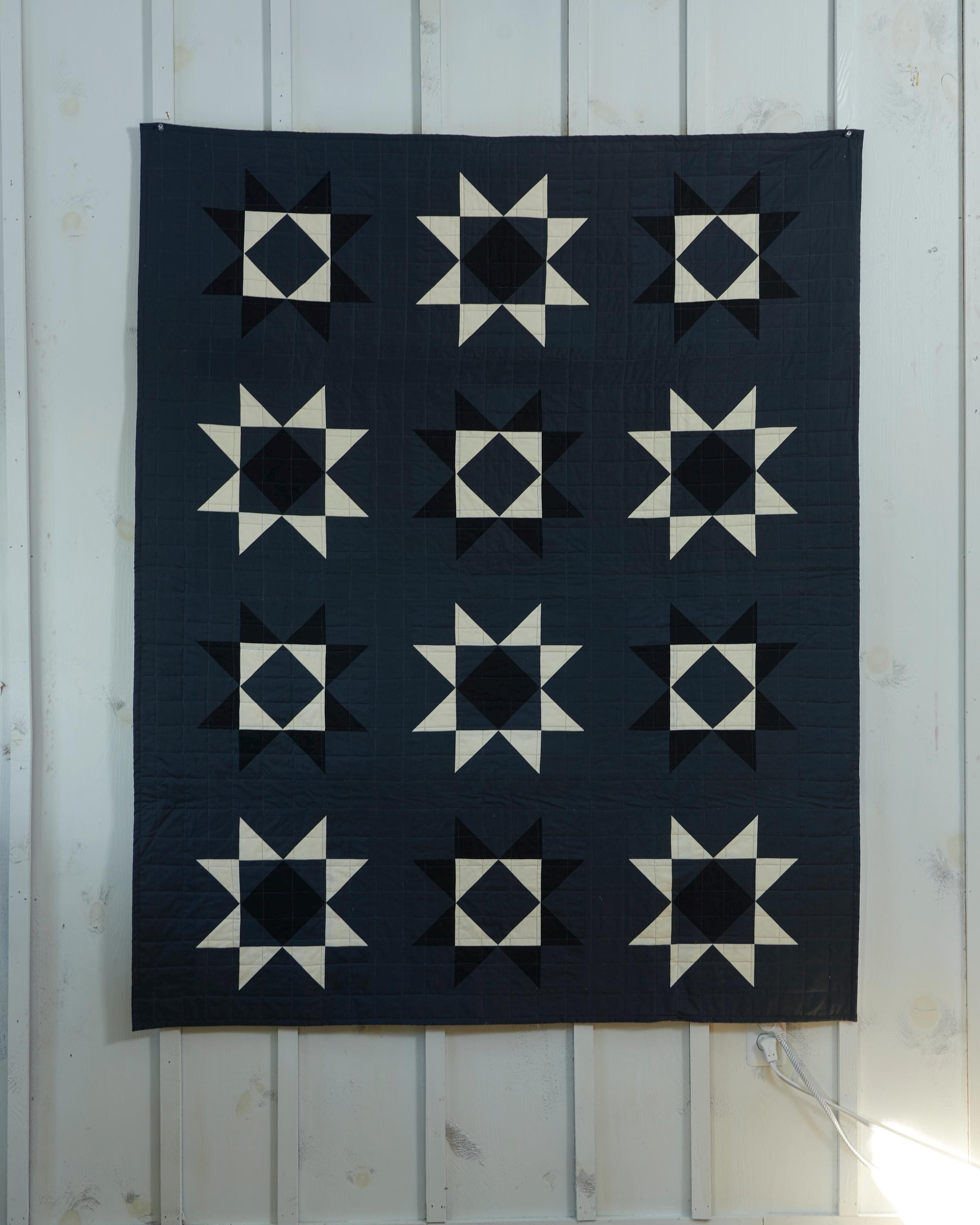 a black and white quilt hanging on a wall