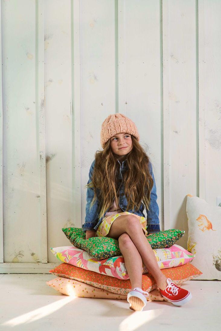a young girl sitting on a pile of pillows