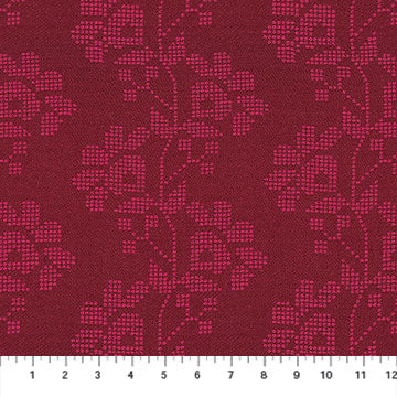 The image is a close-up of a fabric with a repeating floral pattern in shades of red and pink. The pattern consists of stylized flowers and leaves, creating a visually appealing and intricate design. The fabric appears to be a type of textile, possibly used for clothing or home decor.