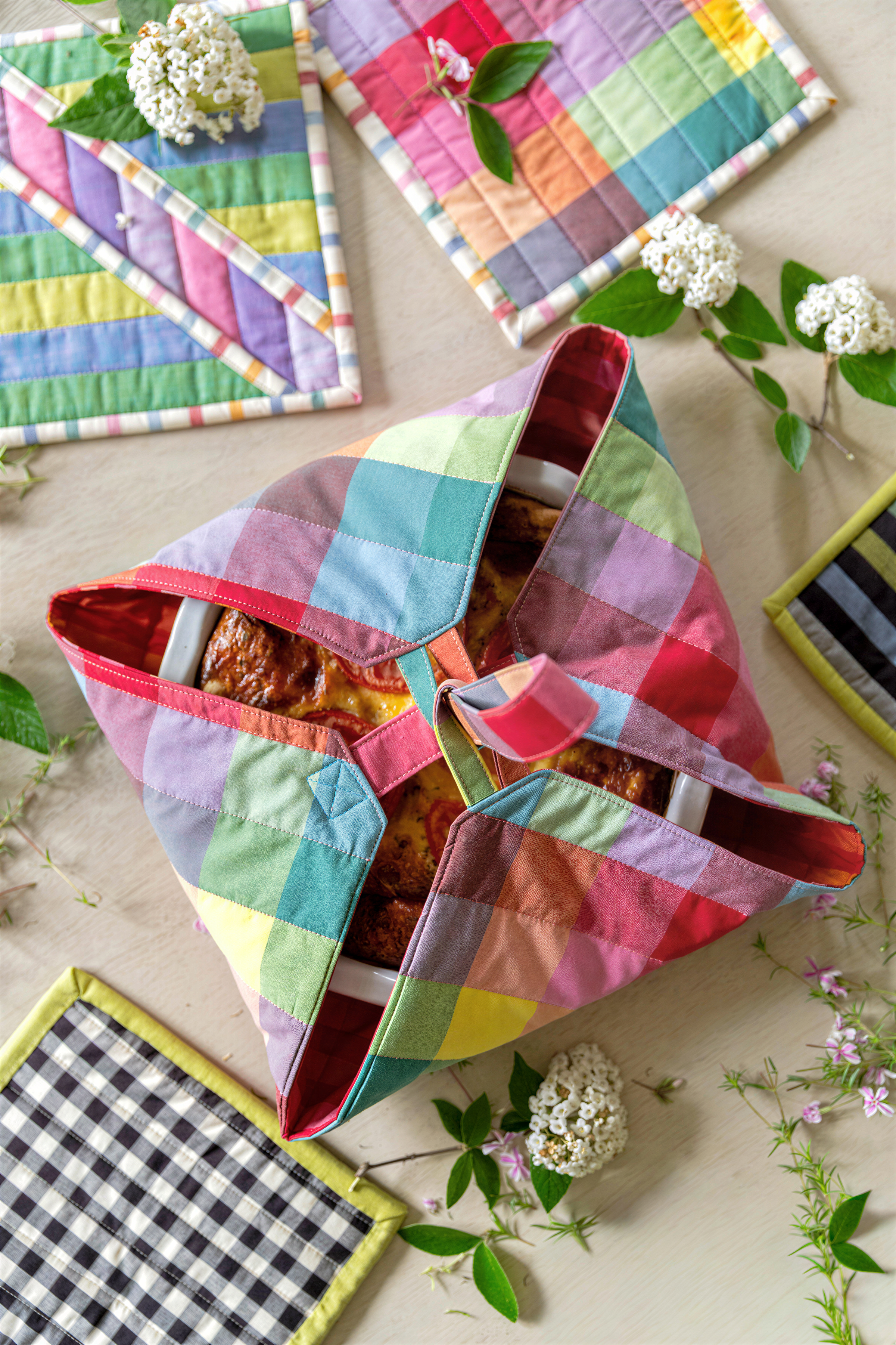 a colorful, plaid-patterned fabric bag with a food item inside, surrounded by various kitchen accessories and flowers.