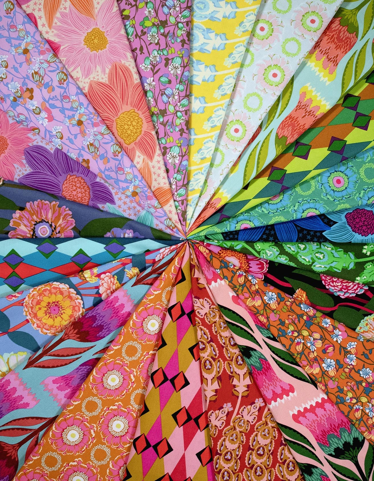 The image is a vibrant collage of various colorful fabric patterns, including floral designs, geometric shapes, and abstract motifs, arranged in a radial pattern.