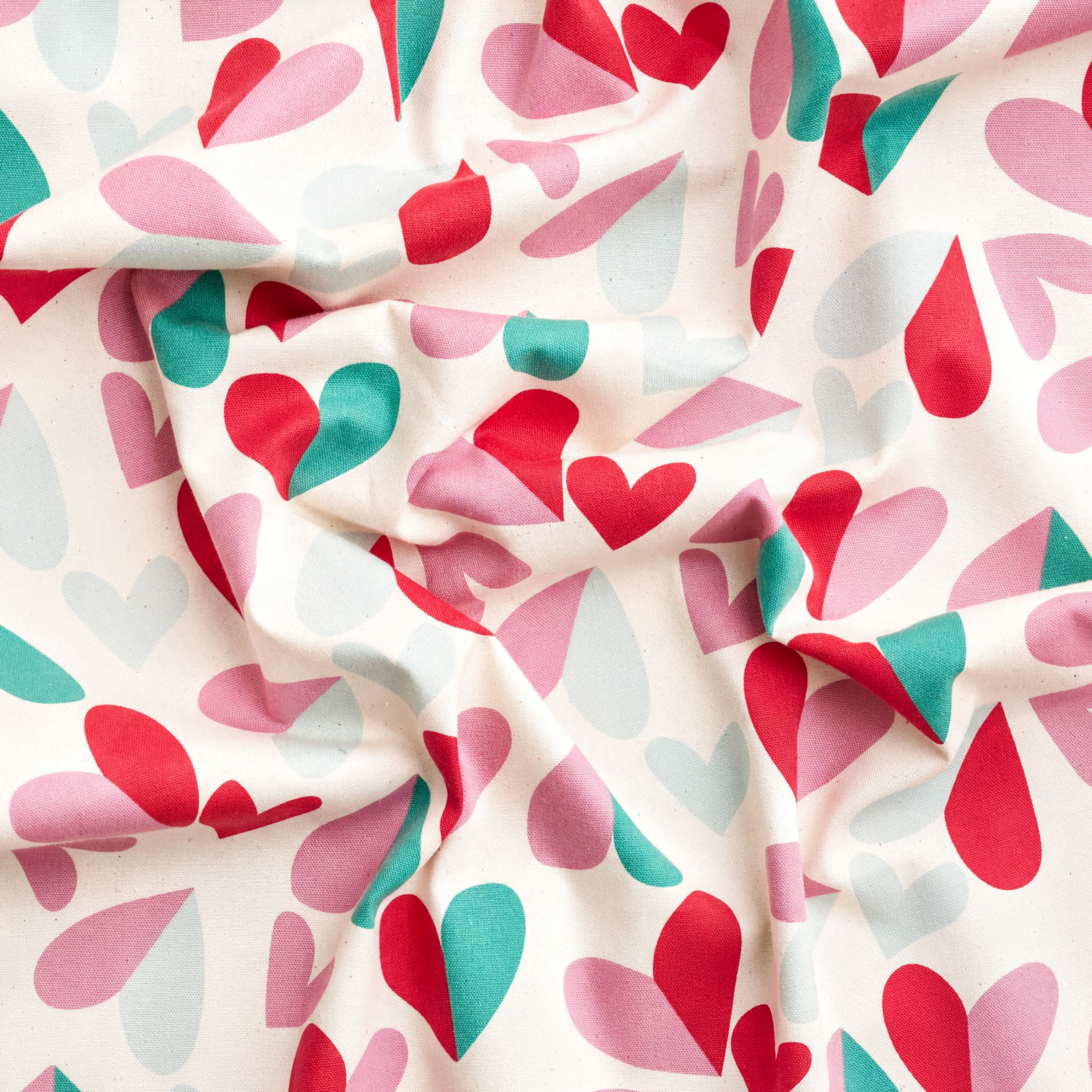 The image is a close-up of a fabric with a repeating pattern of pink, green, and red hearts. The pattern is crumpled and wrinkled, giving the fabric a textured appearance.