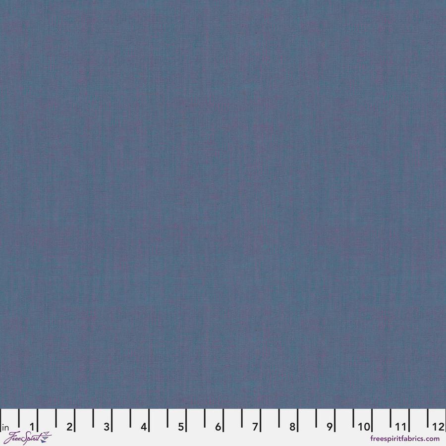 The image is a close-up of a solid blue fabric, with a ruler for scale at the bottom.