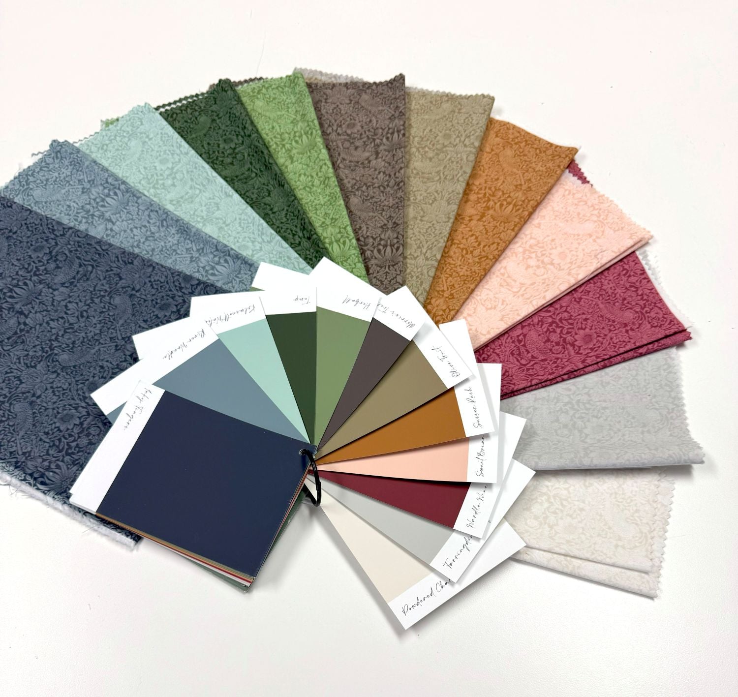 A color swatch book with various fabric swatches arranged in a fan-like pattern, showcasing a range of colors and patterns.