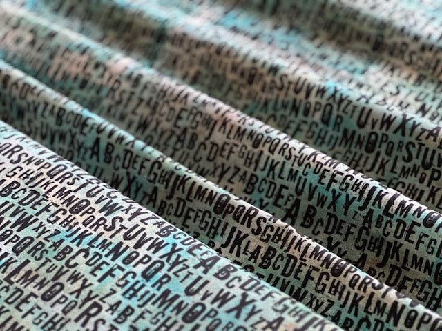 a close-up view of a fabric with a repeating pattern of the alphabet, including the letters A to Z.
