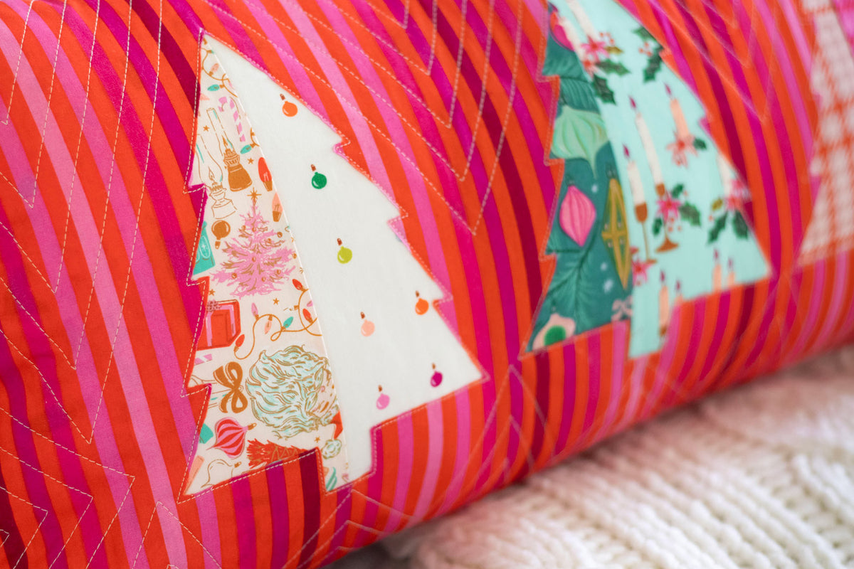 a close-up view of a vibrant, striped pillow with a festive Christmas tree design.