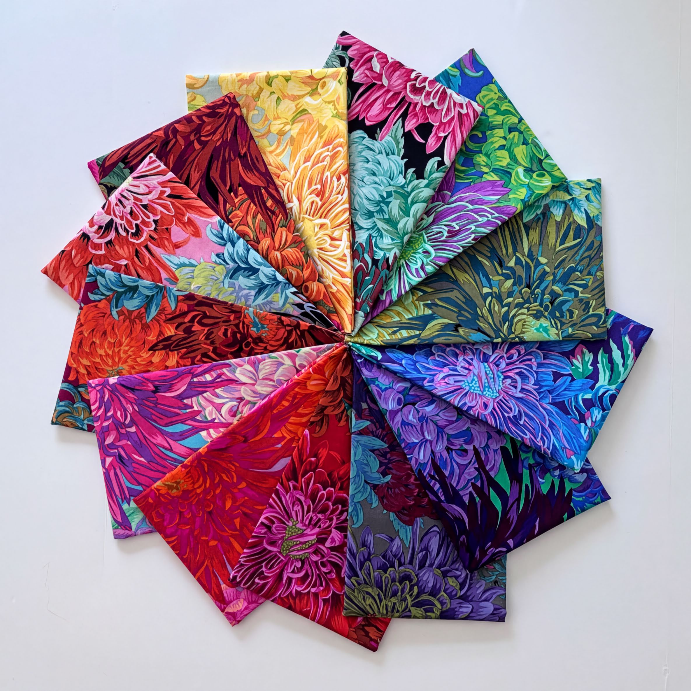A vibrant and colorful arrangement of fabric swatches, featuring a variety of floral and abstract patterns in a range of bright and vivid colors.
