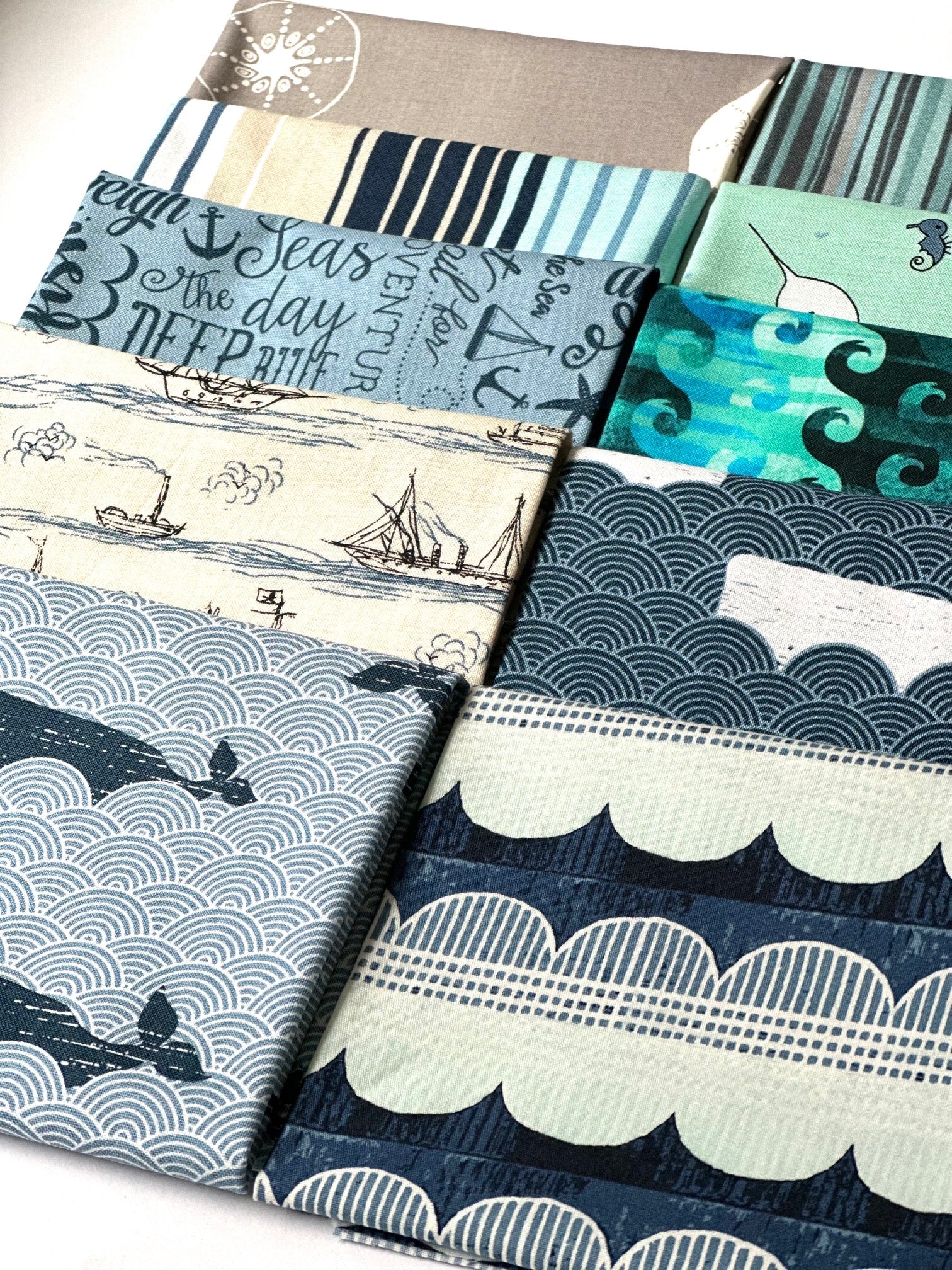 a collection of fabric swatches with various patterns and designs, including ocean-themed patterns, such as waves, ships, and marine life.