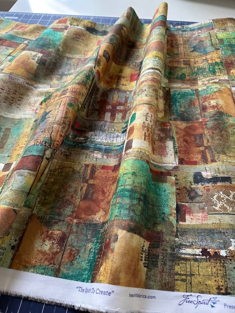 The image is a close-up view of a colorful, abstract fabric with a variety of patterns and textures. The fabric appears to be folded or rolled, revealing its intricate design.