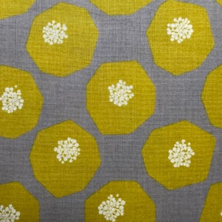 a repeating pattern of yellow octagonal shapes with white flowers or buds on them, arranged in a grid-like pattern against a gray background.