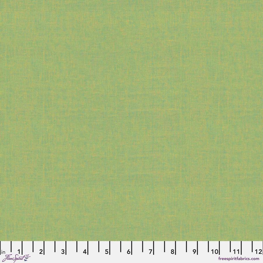 The image is a close-up of a solid green fabric with a ruler for scale.