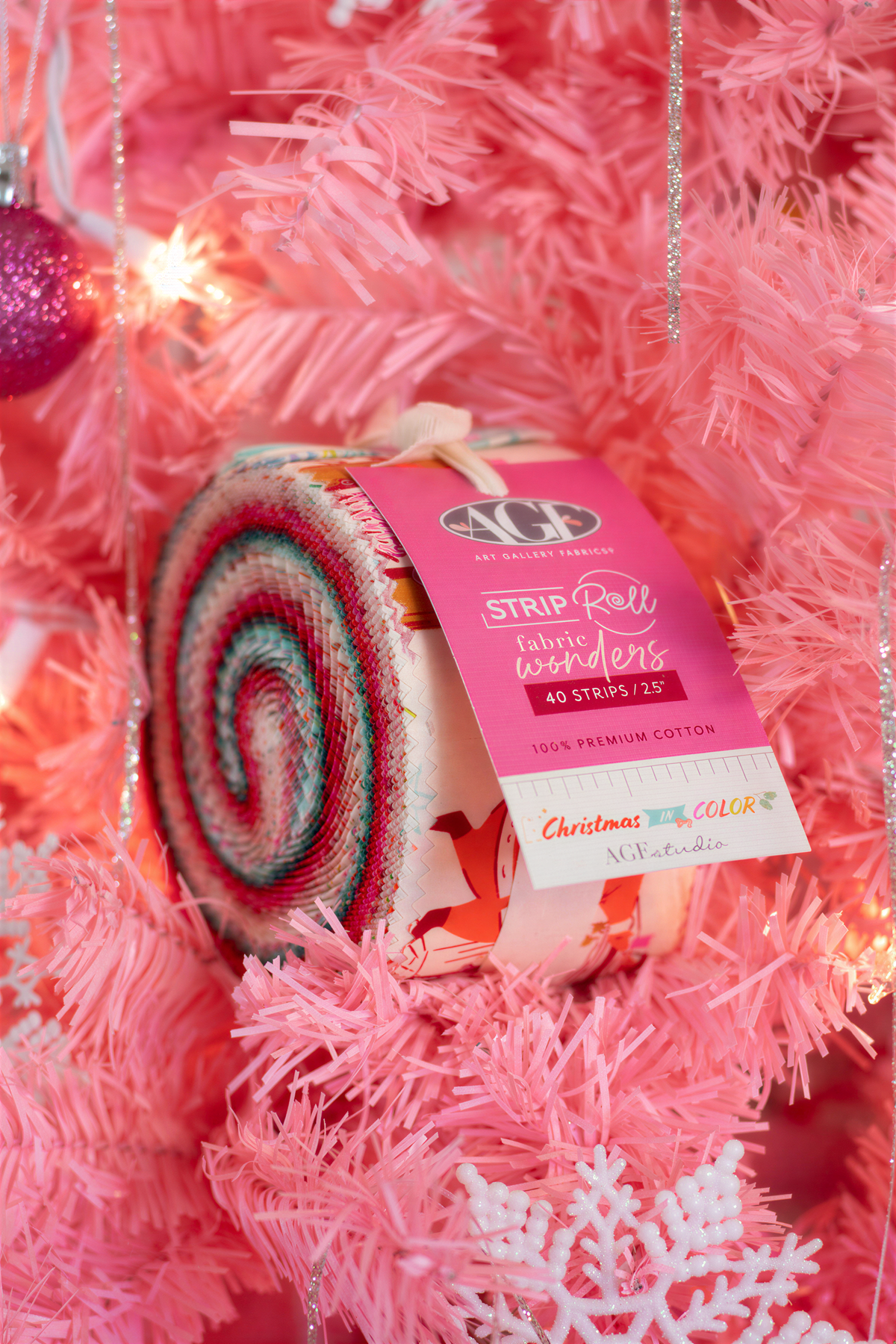 A close-up of a Christmas tree with a pink and white striped fabric wrapped around it, and a pink and white label attached to the tree.
