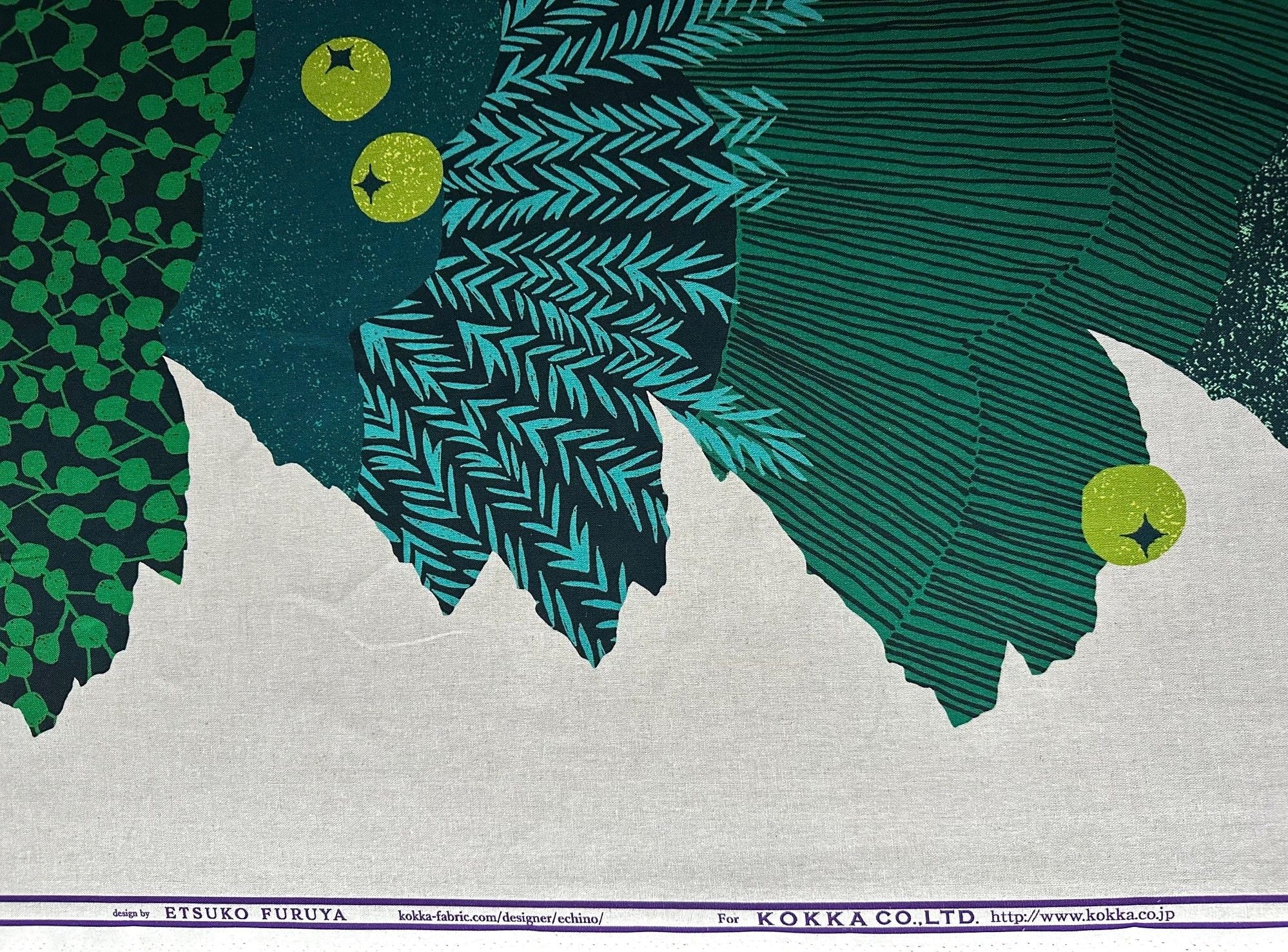 The image is a textile print featuring a vibrant abstract design with green and blue elements, including leaf-like shapes and geometric patterns.